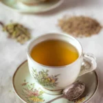 Cup of CFC tea served in a vintage floral teacup with cumin, fennel, and coriander seeds in the background