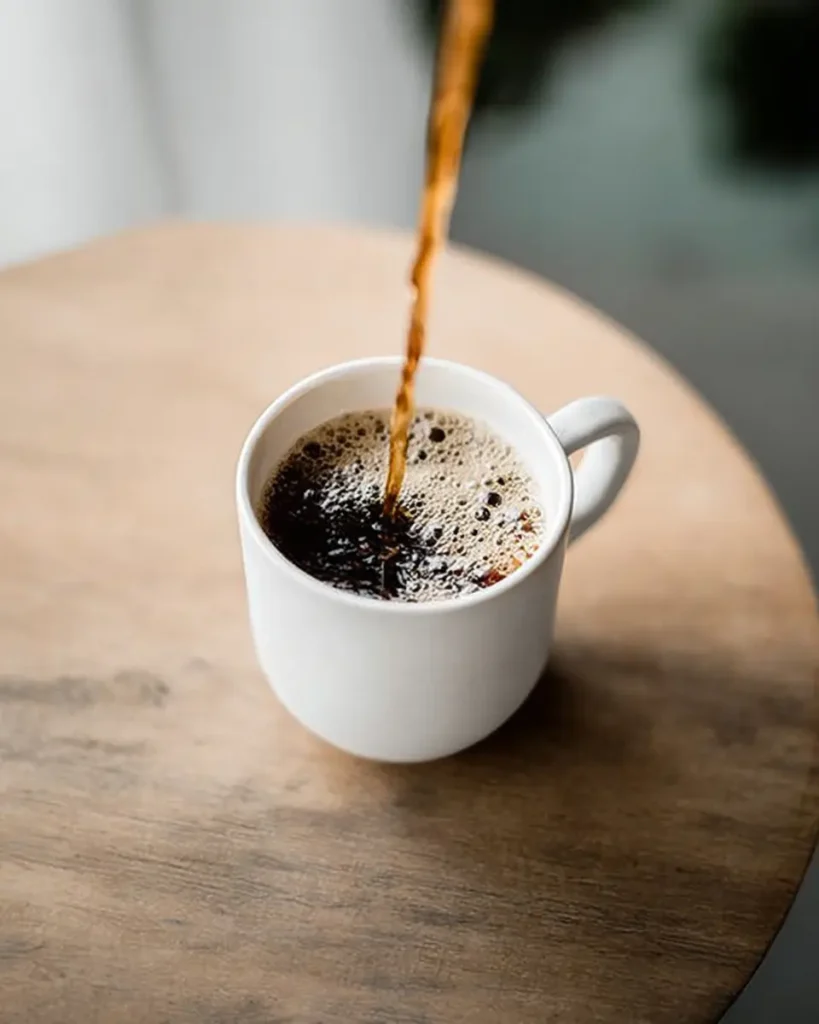 Coffee Loophole Recipe – Energizing Weight Loss Coffee That Works Fast 10 Coffee loophole recipe being poured into a white cup on a light wooden table, with visible froth and a cozy morning background