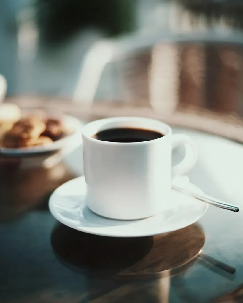 Coffee Loophole Recipe – Energizing Weight Loss Coffee That Works Fast 7 Hot cup of the coffee loophole recipe on a saucer with spoon, styled on a glass table with warm morning lighting and soft background blur.