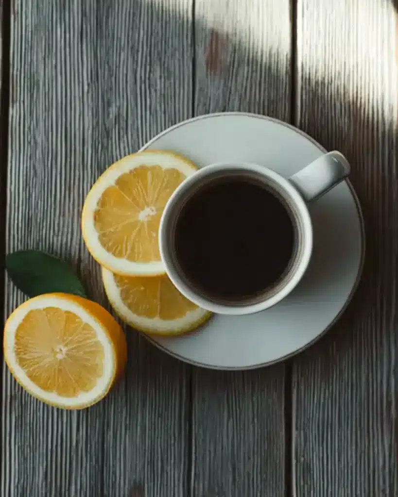 Coffee Loophole Recipe – Energizing Weight Loss Coffee That Works Fast 8 Top-down view of the coffee loophole recipe with lemon slices in a white cup on a rustic wooden table, styled with a halved lemon nearby.