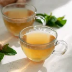 Tummy Tea Recipe for Belly Bloat, Digestion & Weight Loss Support 12 Clear glass cups of tummy tea with fresh mint and ginger on a light surface in natural light