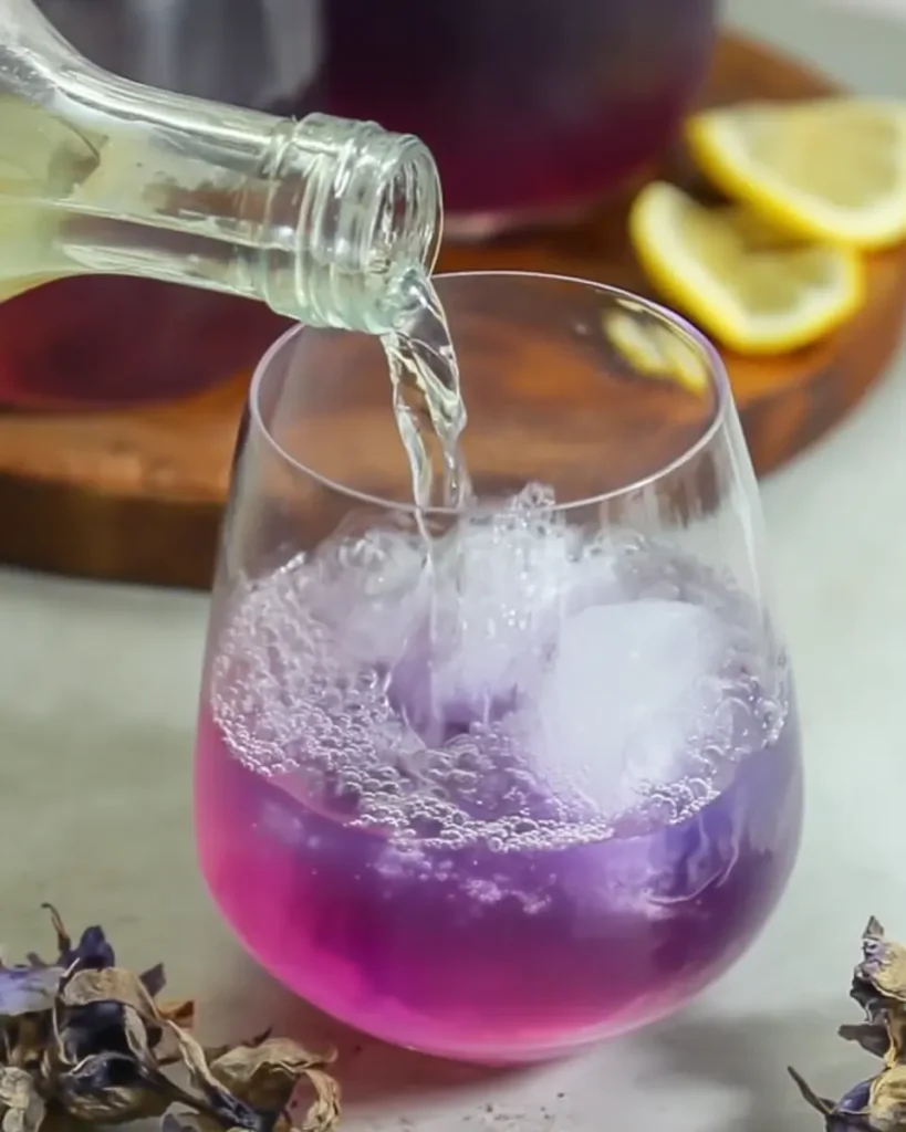 Butterfly Pea Tea Lemonade – Brilliant & Refreshing Recipe 17 Butterfly pea tea lemonade with soda water being poured over ice in a clear glass
