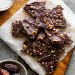 Date Bark Recipe: Easy, Healthy & Viral No-Bake Treat 9 Homemade date bark pieces with dark chocolate, peanuts, and flaky sea salt on parchment paper.