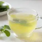 Lemon balm recipe for weight loss tea in a clear glass cup with fresh lemon balm leaves