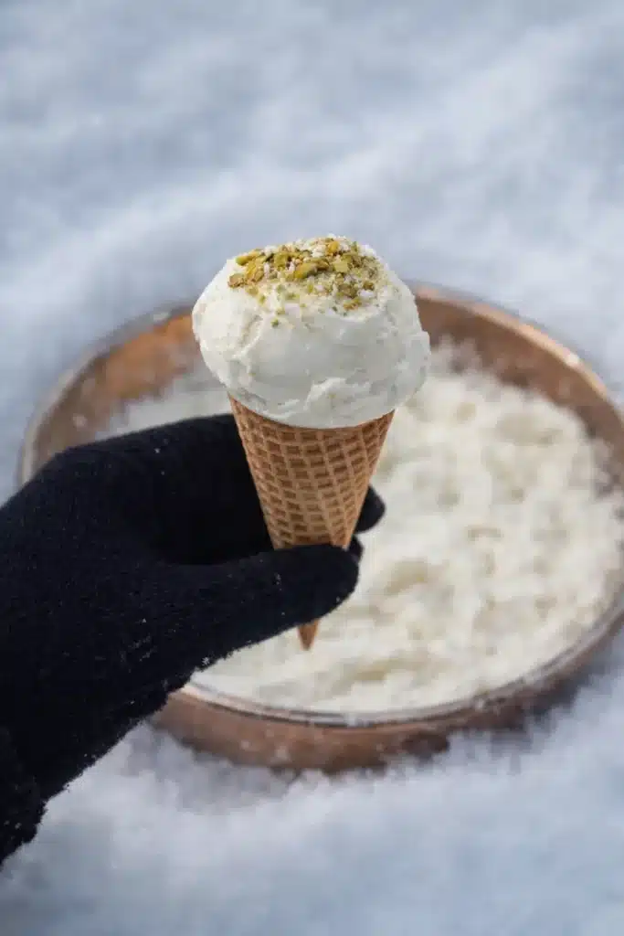 Viral snow ice cream in a waffle cone held with a glove, made with the salted snow bowl TikTok method.
