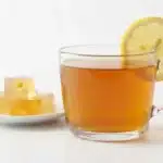 Collagen Gelatin Trick glass mug of amber gelatin tea with lemon and a plate of gelatin cubes on a white surface