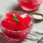 Keto Jello for Weight Loss in a glass bowl with sugar free red gelatin cubes and fresh herb garnish