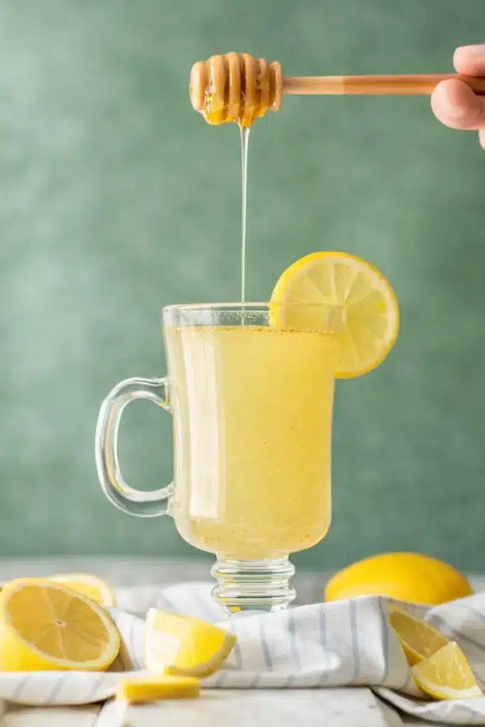 Master cleanse recipe honey drizzle into lemon detox drink in a glass mug with lemon slice