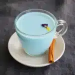 Moon milk tea recipe card photo with pastel blue butterfly pea milk tea and cinnamon on a saucer
