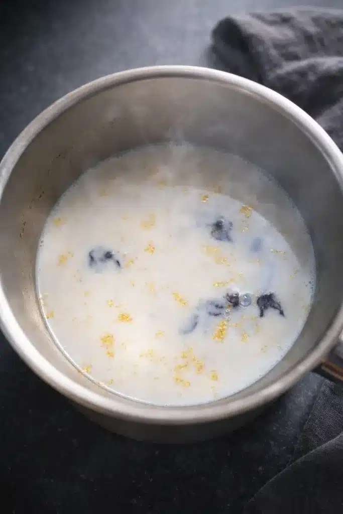 Moon Milk Tea – A Magical Blue Bedtime Drink 11 Moon milk tea milk warming in a saucepan with butterfly pea pieces and golden flecks