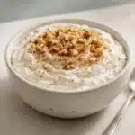 Budwig recipe cottage cheese bowl topped with cinnamon and chopped nuts in a ceramic ramekin